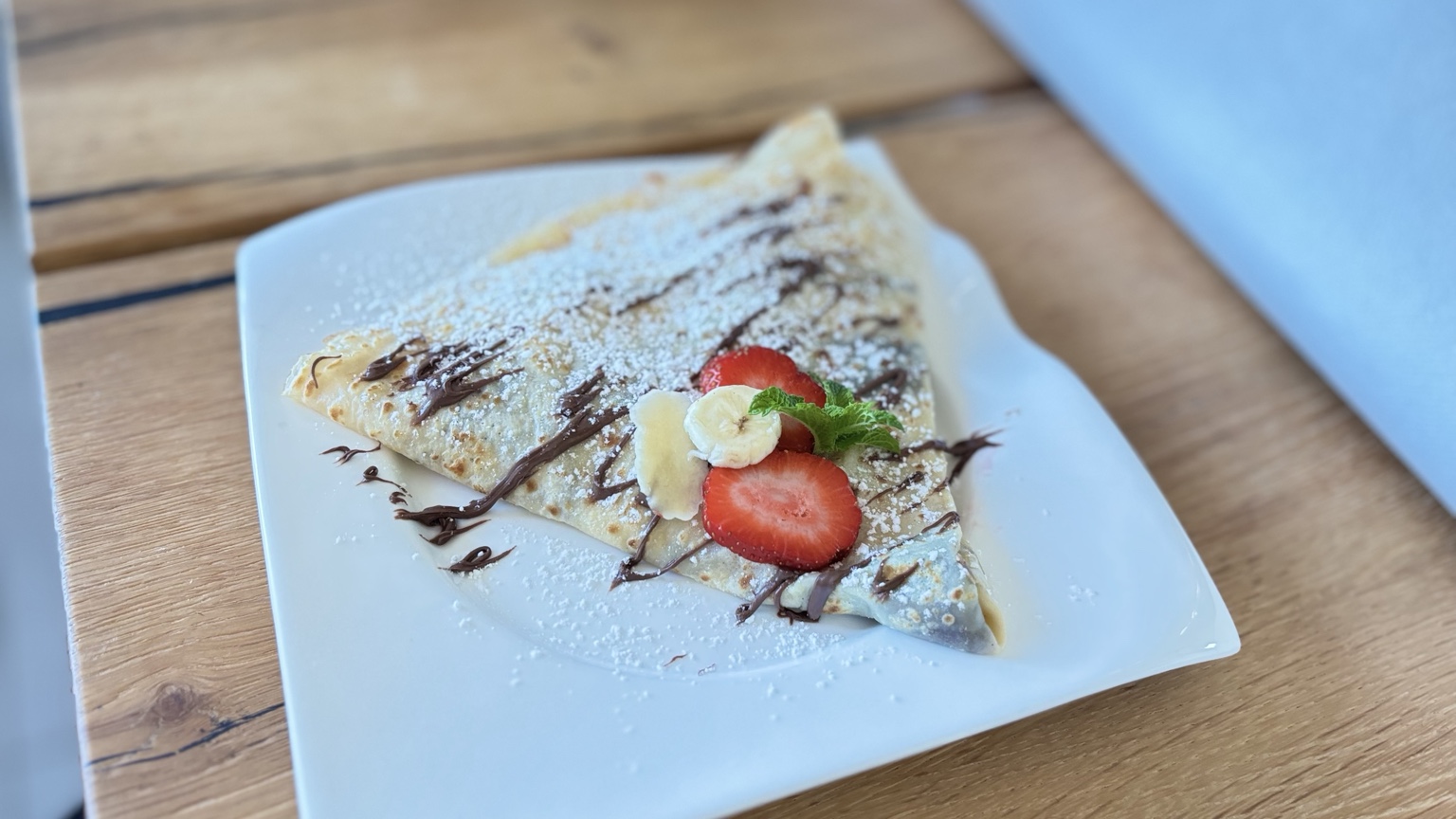 Frisch gebackener Nordlicht Crêpe mit Nutella, Puderzucker, Erdbeeren und Banane