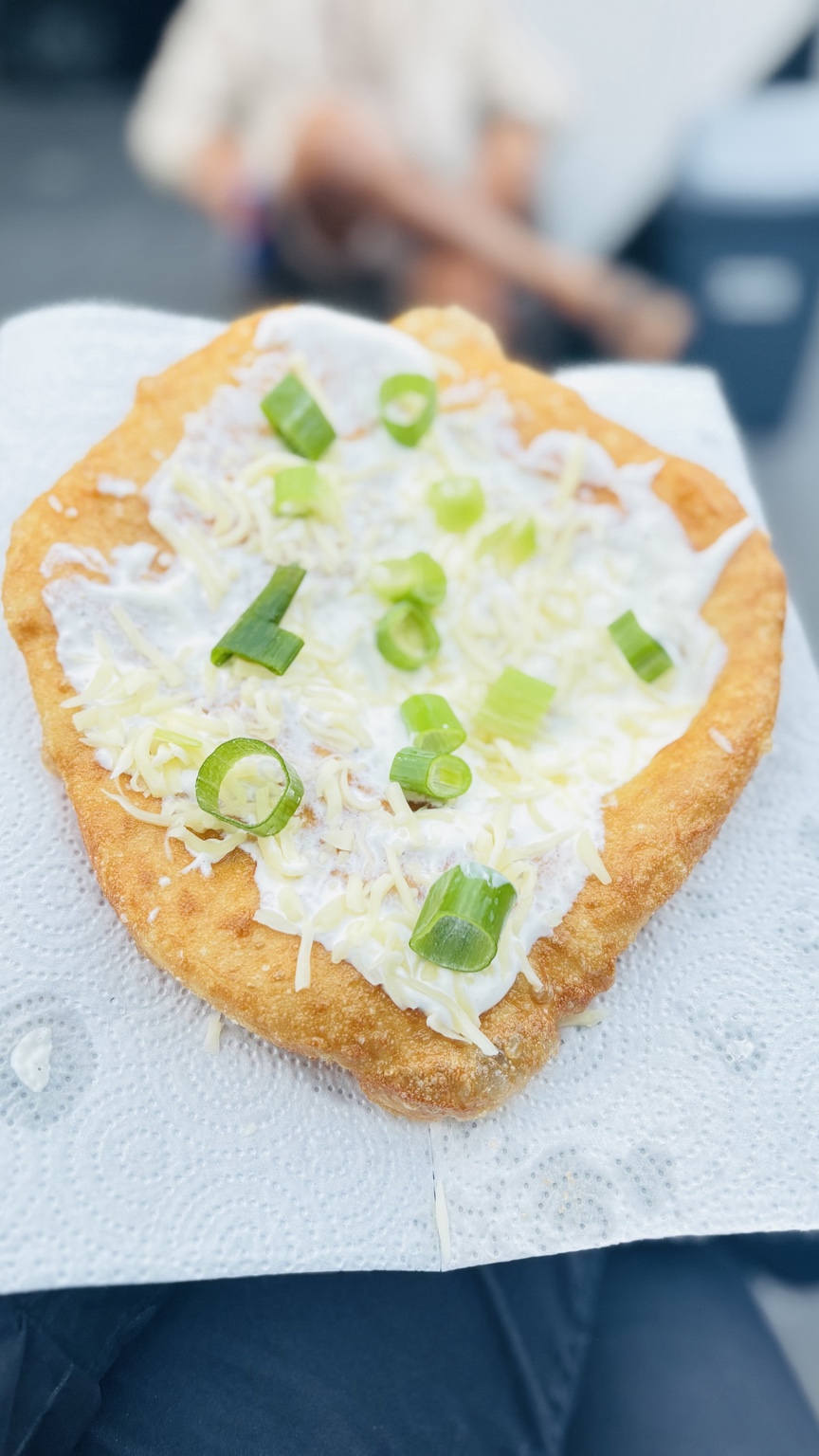 Frisch ausgebackener Langos mit Knoblauchcreme, Käse und Frühlingszwiebeln